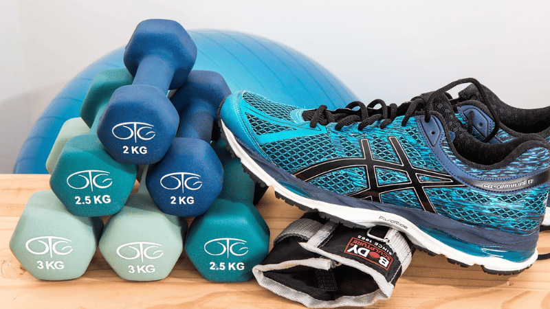 テーブルに置かれた鉄アレイとシューズ、手首サポーター