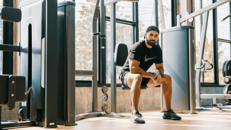 ジムのマシンに腰かけている男性