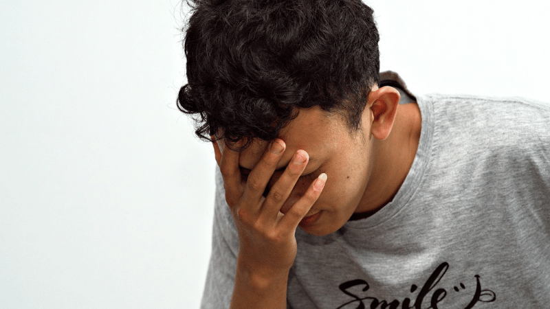 右手で顔を覆いうなだれる男性
