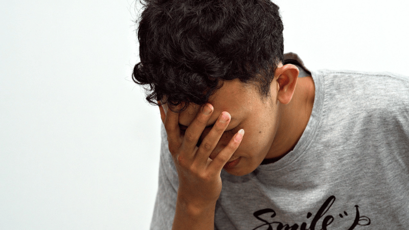 顔を覆いうなだれる男性