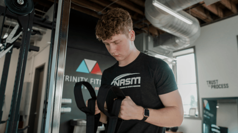 ジムの器具を準備しているパーソナルトレーナー男性