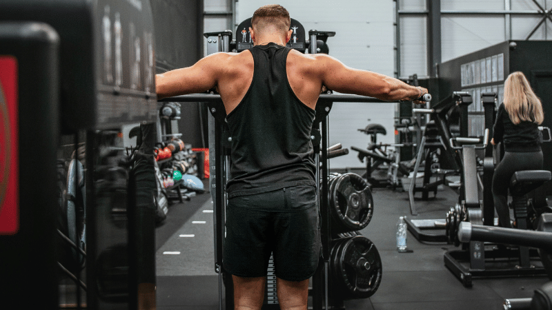 スポーツジムのマシンで筋トレをしている男性